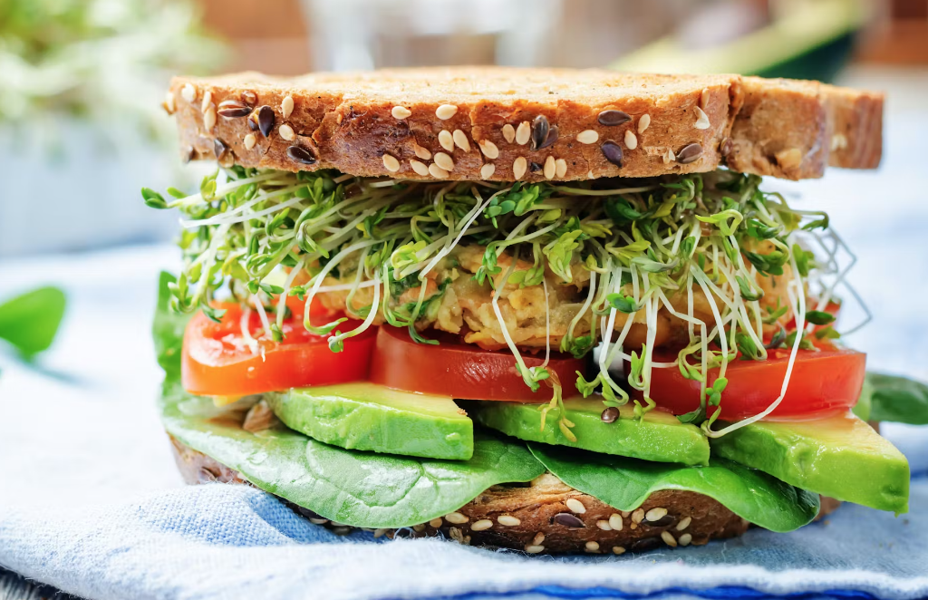 sandwich with fresh sprouts, avocado, and tomatoes